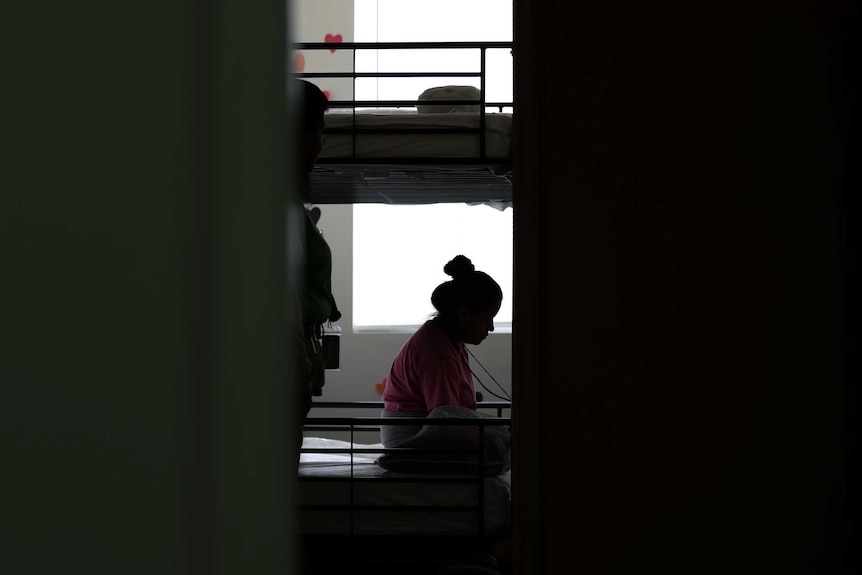 A girl in silhouette sits on a bunkbed