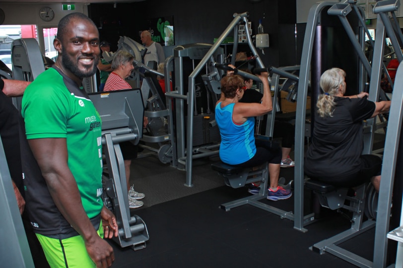 Kay smiling while seniors work on gym machines in the background