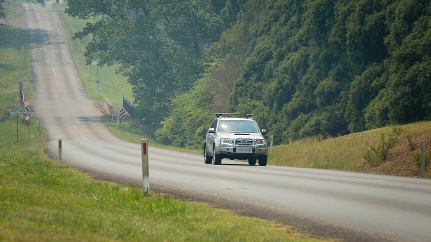 A Subaru drives along a country road.