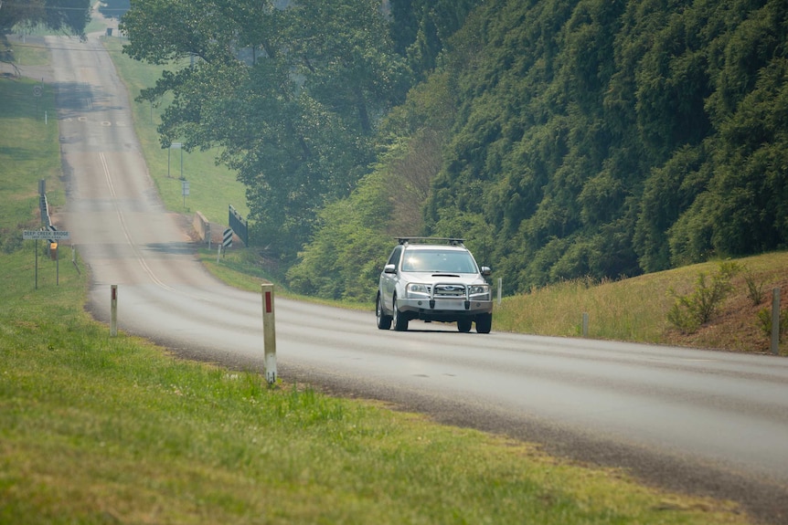 A Subaru drives along a country road.