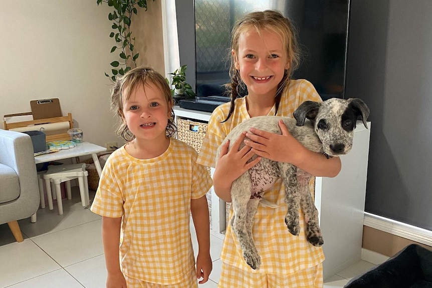 Two girls smiling holding a puppy