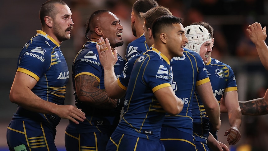A group of rugby league players celebrate scoring a try