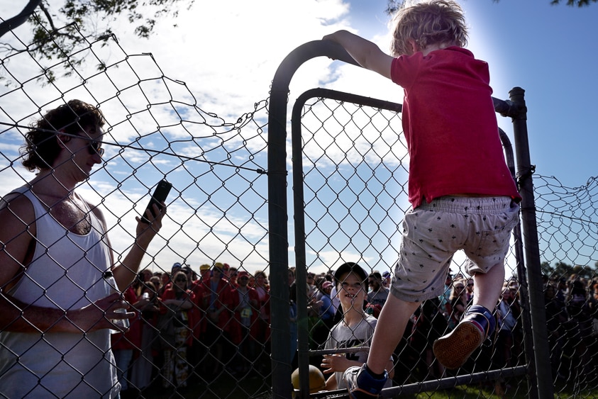 A young boy scales the event fence to re-join his dad after escaping the big line waiting to get in.