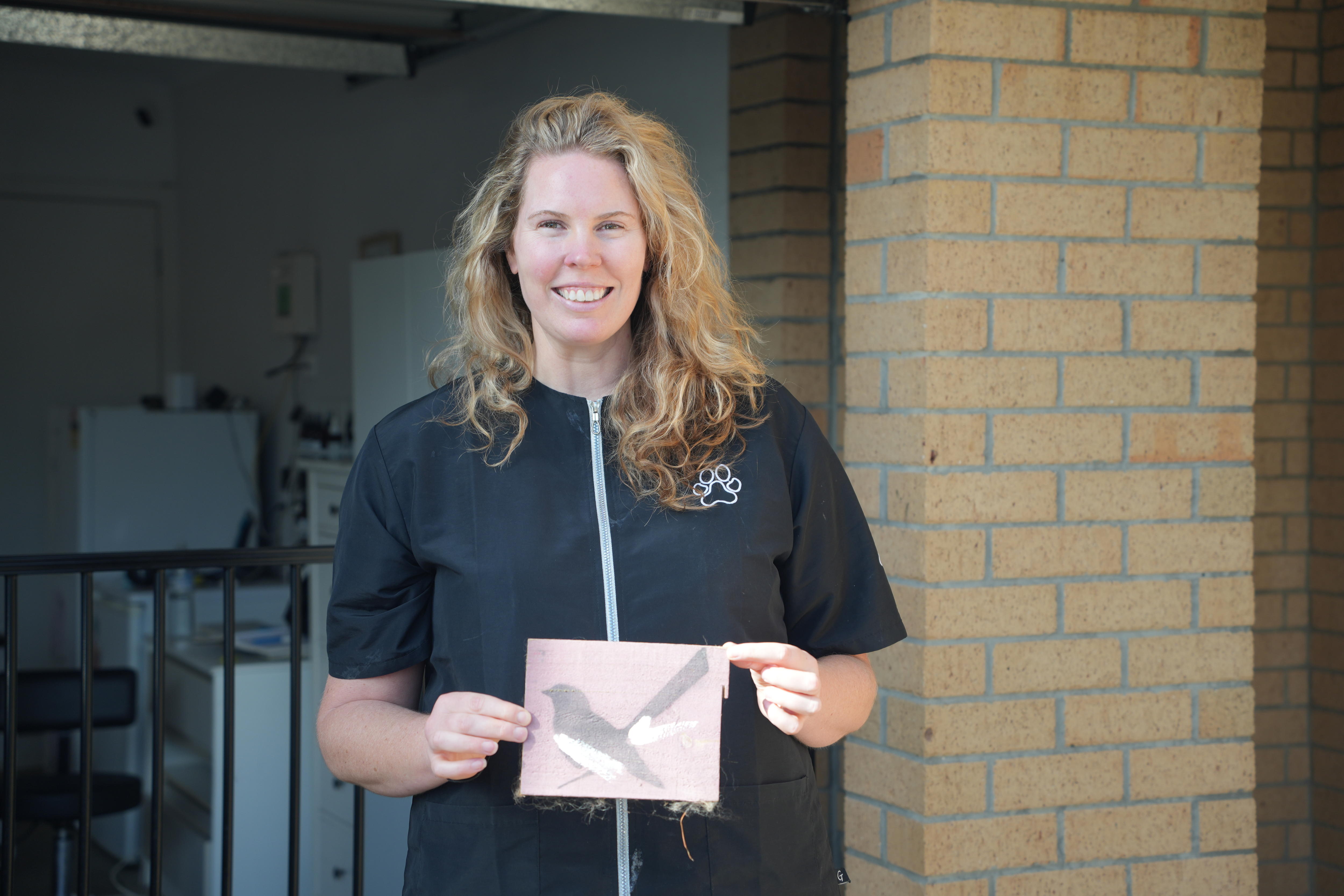 Sally Sexton holds up a pink willie wagtail painting.