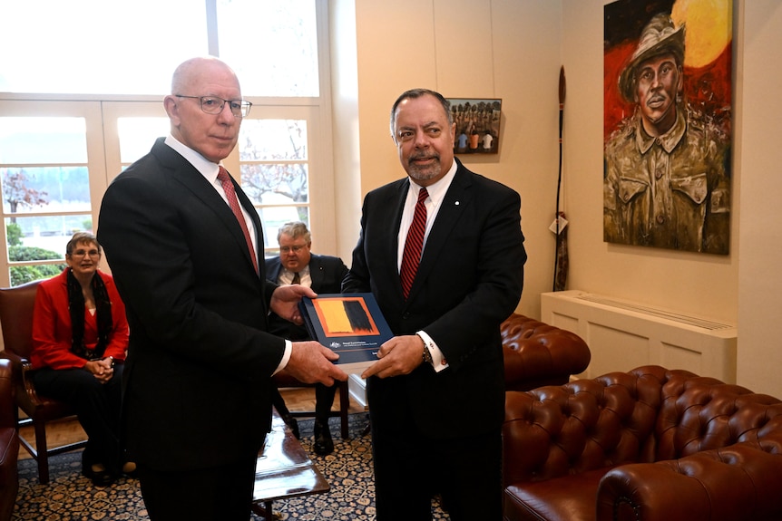 A commissioner and the Governor-General hold a report between them in an office.
