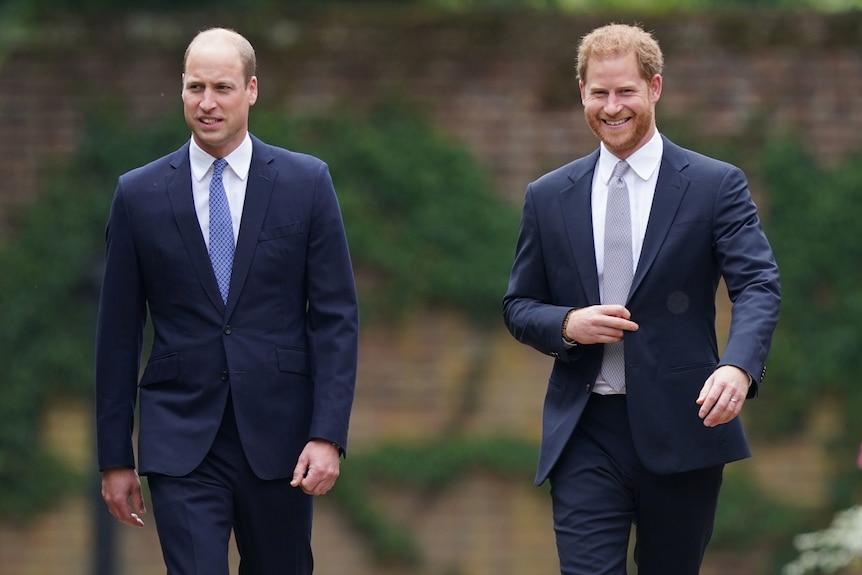 Il principe William e il principe Harry sorridono mentre camminano mano nella mano.