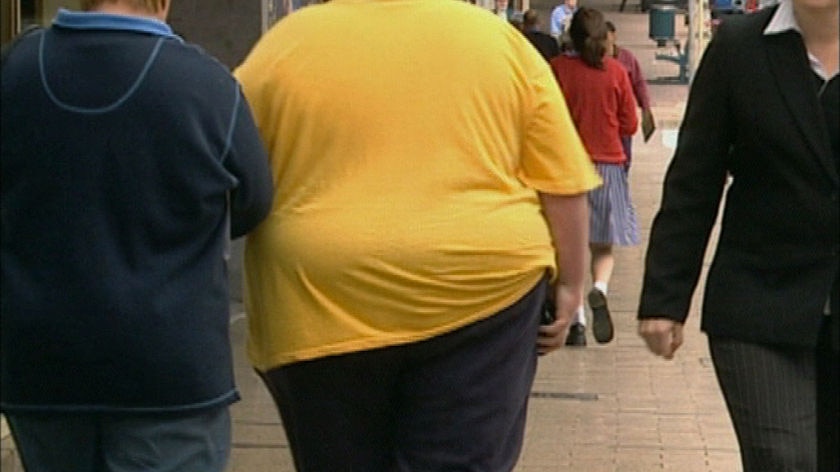 An obese woman walks down a street