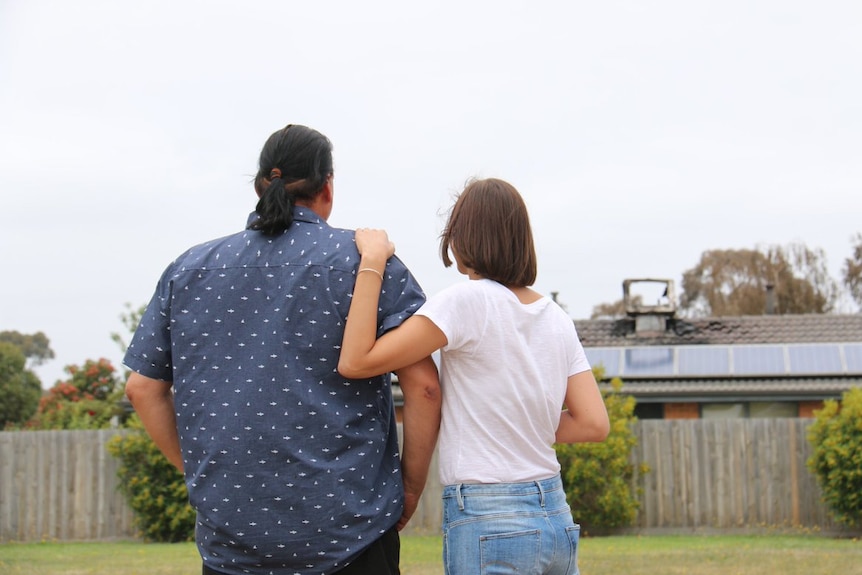 Jim Crozier and his daughter look back on his fire-damaged house at Carrum Downs.