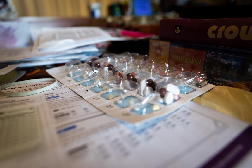 Pre-packaged medication separated by date and time sitting on a cluttered table.