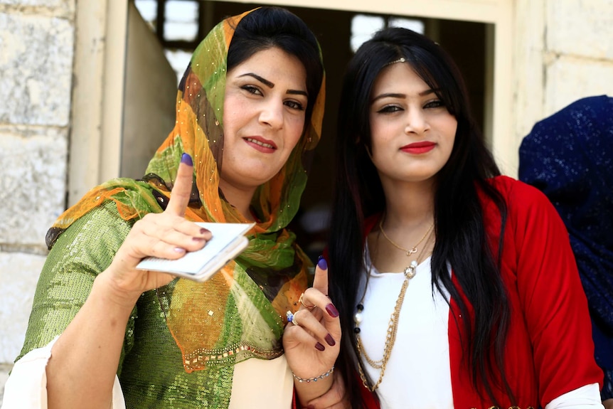 Kurdish women show their ink-stained fingers after voting.