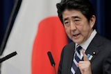 A close up of Abe with the red circle of a Japanese flag in the background