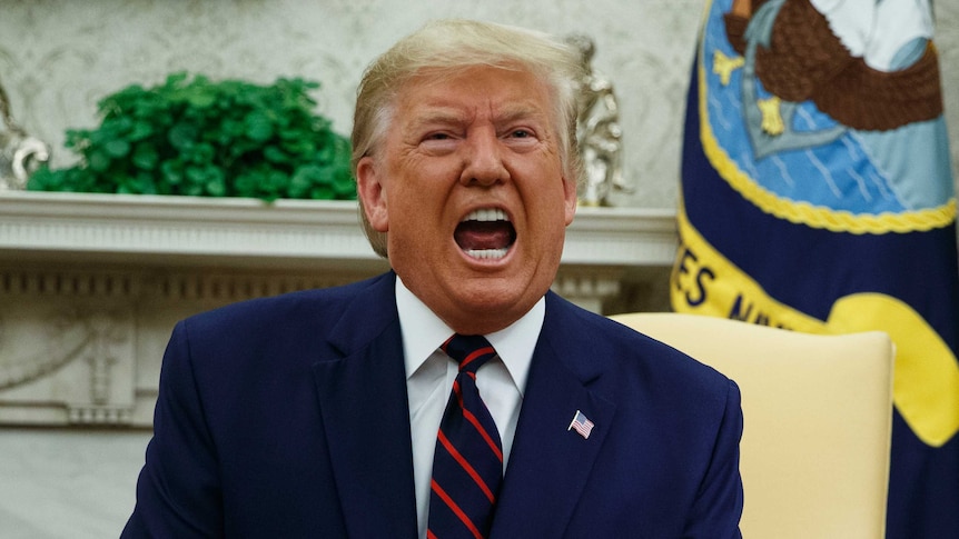 President Donald Trump appears to be yelling as he sits on a chair facing the camera.