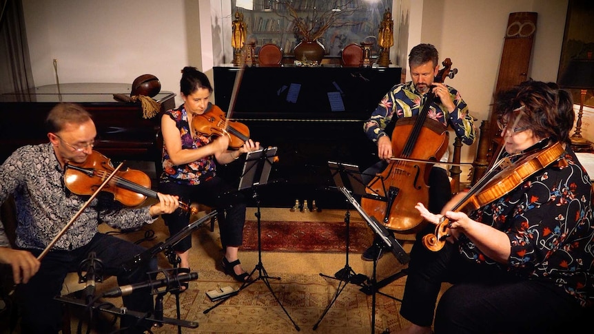 A string quartet play in a small studio surrounded by Asian and Western instruments.