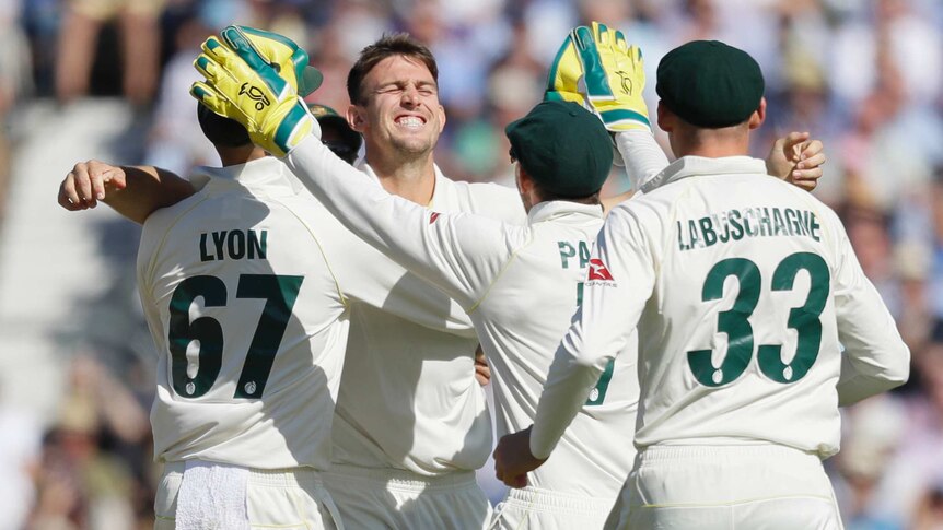 Mitch Marsh smiles widely as he is congratulated by a number of his teammates.