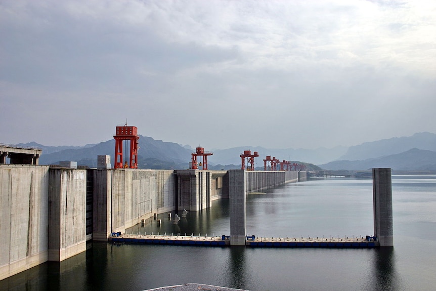 You view across a dammed Yangtze River on an overcast day with mountains in the distance.