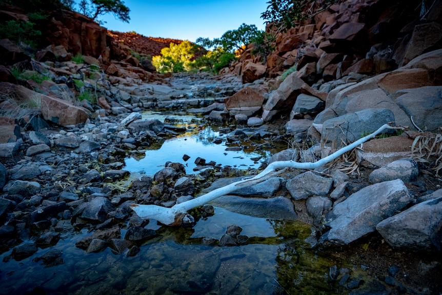 A stream through rocky country reflects the sun.