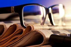 Glasses sit on top of a pile of newspapers (Thinkstock/Getty Images)