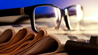 Glasses sit on top of a pile of newspapers (Thinkstock/Getty Images)