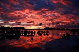 Villagers watch the sunset over a small lagoon in Kiribati.