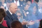 Peter Dutton holds out his arms at a smoking ceremony outside parliament house
