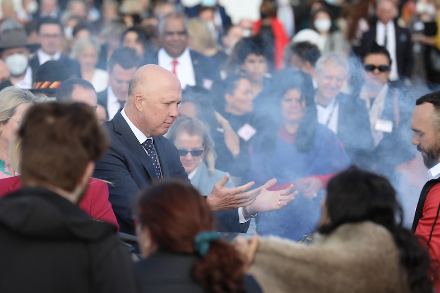 Peter Dutton holds out his arms at a smoking ceremony outside parliament house