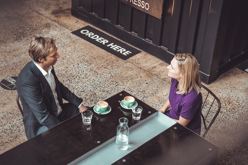 Man and woman have coffee at a cafe seen from above.
