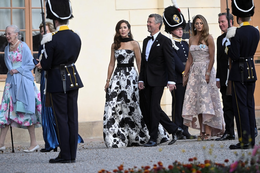 Crown Princess Mary wearing a ballgown and Crown Prince Frederik wearing a dark suit arrive at a palace.