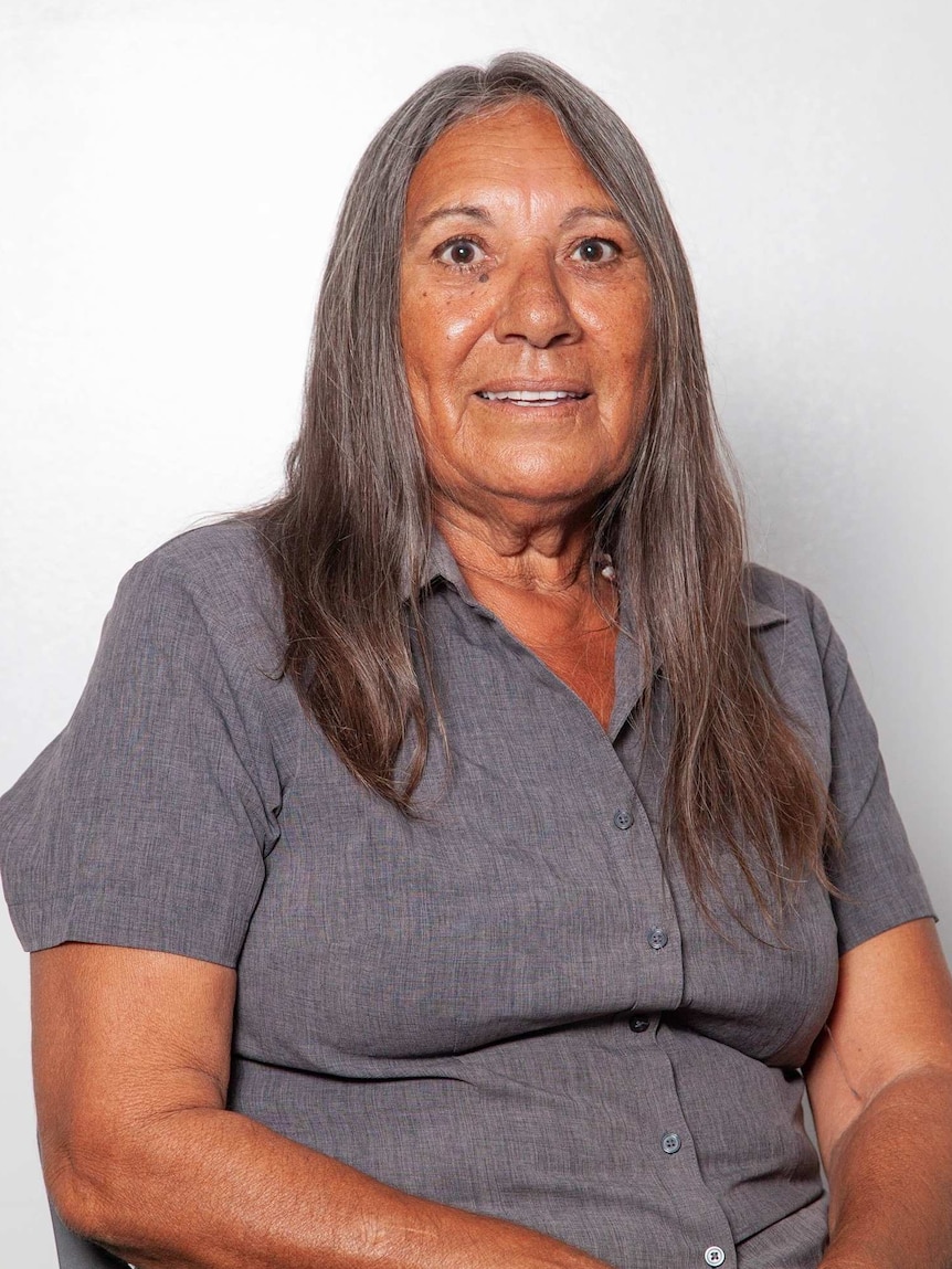 Head and shoulders image of an older woman in a grey shirt against a white background.