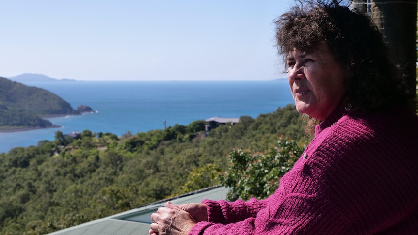 Woman on her veranda looking out at her view of the ocean. 