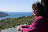 Woman on her veranda looking out at her view of the ocean. 