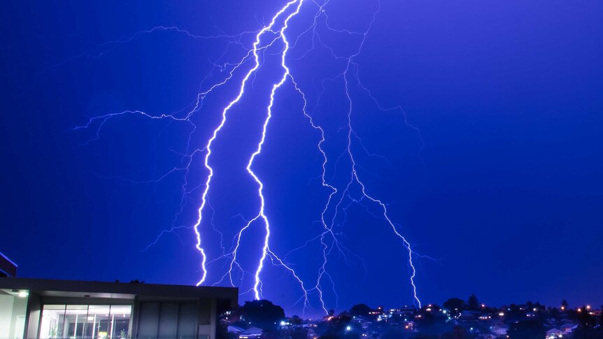 Lightning bolts turn the night sky bright blue