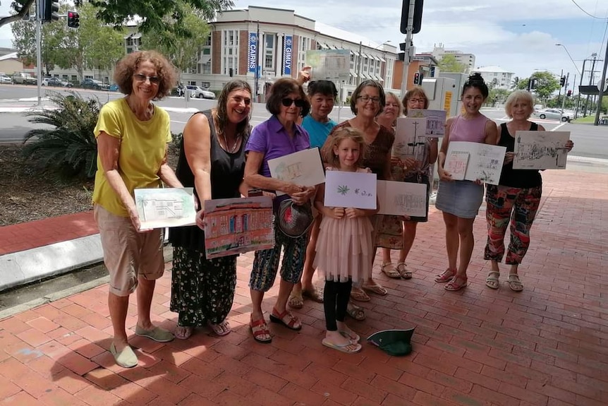 group of people holding artwork in their hands standing on street corner