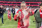 A woman tips a bag of ashes onto the SCG.