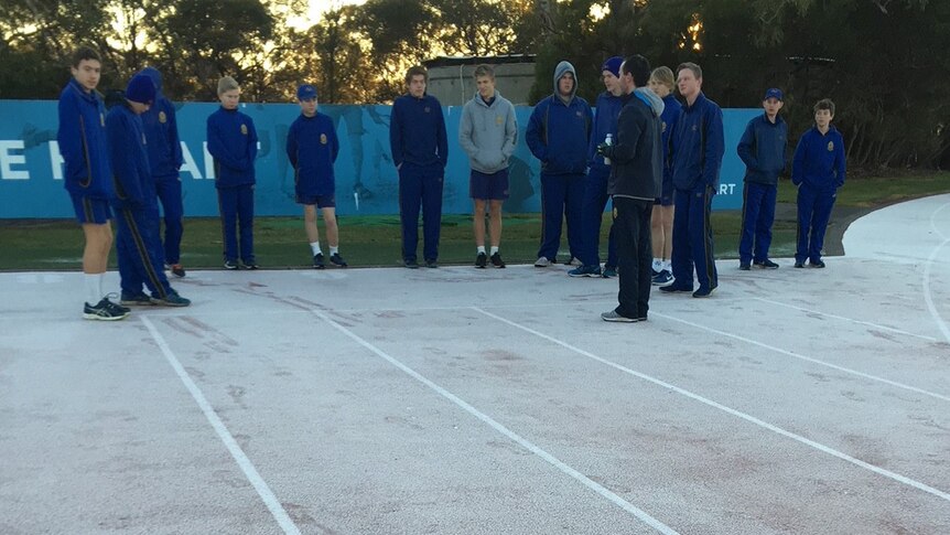 Schoolboys look over the frosty running track on cold August morning.