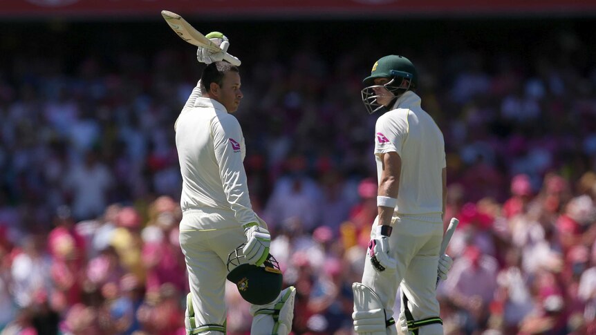 Usman Khawaja raises his bat while Steve Smith looks at him out on the SCG.