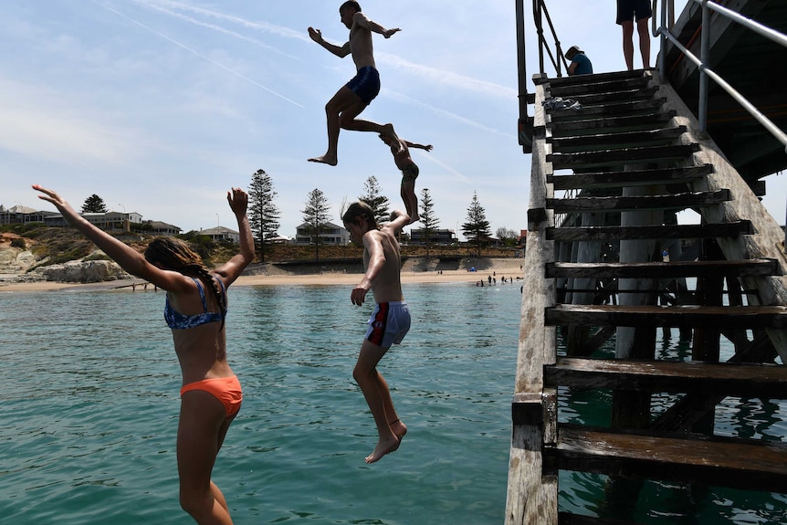 People jump from a jetty into the ocean in South Australia.