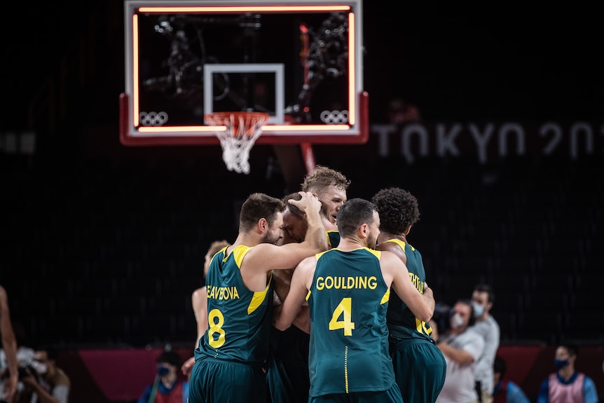 A group of Australian basketballers gather mid-court for a celebratory hug after winning an Olympic bronze medal. 