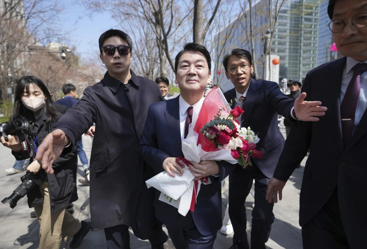 Ahn Cheol-soo holding a bouquet of flowers and walking through a crowd