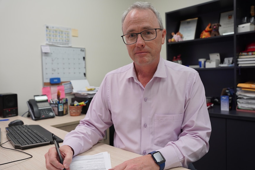 A man wearing glasses sitting at a desk