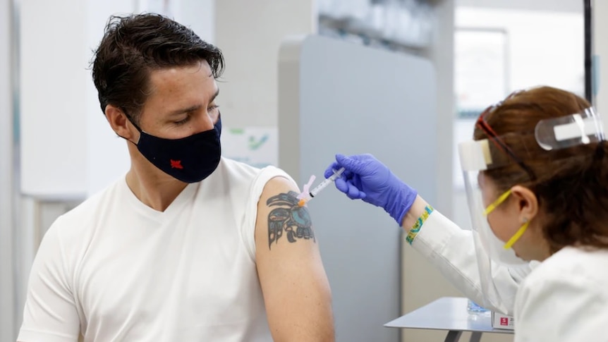 A man with a tattoo being jabbed with a vaccine by a healthworker.