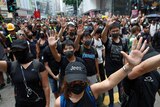 Protesters wear black clothes and hold their hands out as they march