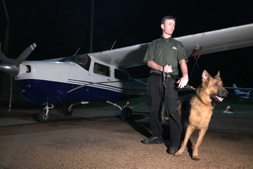 A security guard stands with a dog in Galiwin'ku.