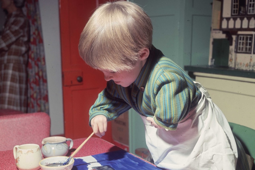 A long girl with short limbs affected by thalidomide paints a picture.