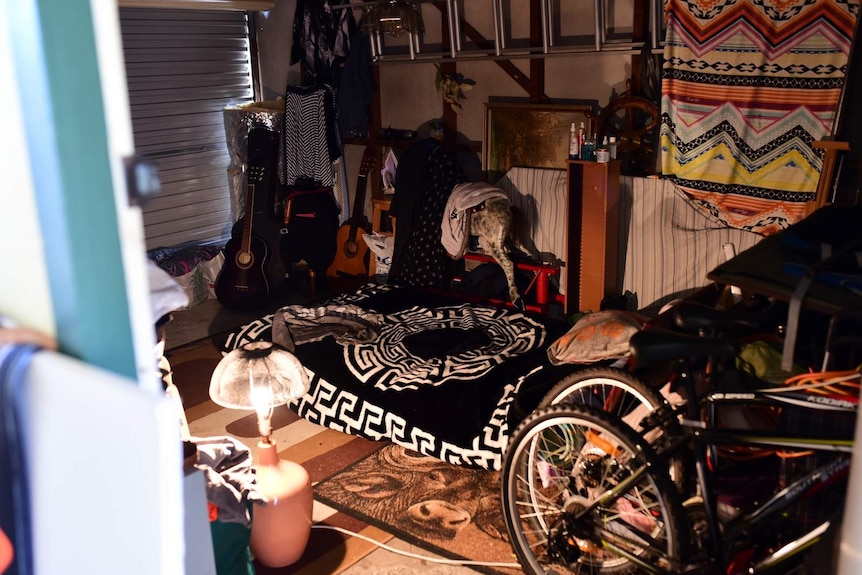 A messy garage with a mattress and various items on the floor