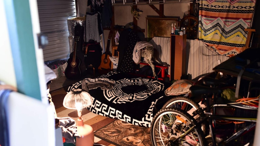 A messy garage with a mattress and various items on the floor