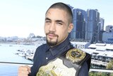 Robert Whittaker with the UFC middleweight belt held on his shoulder.