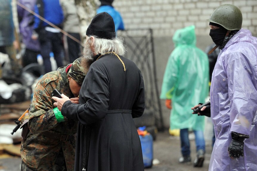 Armed pro-Russian protester kisses a cross
