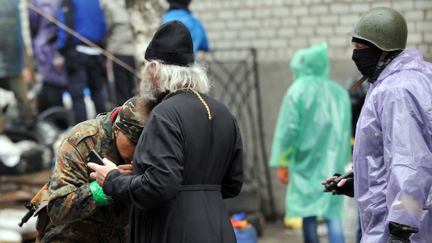 Armed pro-Russian protester kisses a cross