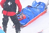 An Australian snowboard cross athlete on a stretcher at the Beijing Winter Olympics.