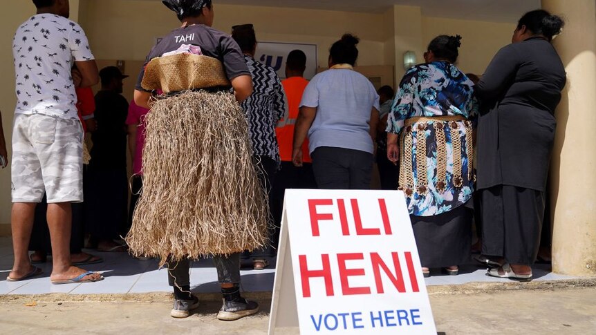 A woman wearing a grass skirt is among voters queueing at a polling station in Tonga.